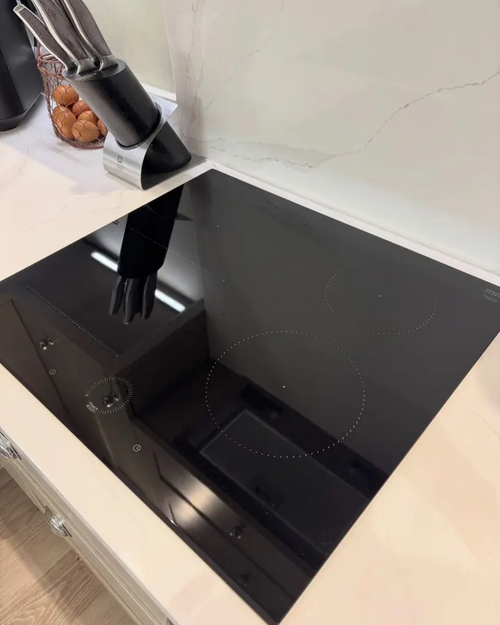 A black induction hob on a marble worktop, wiped to a mirror finish