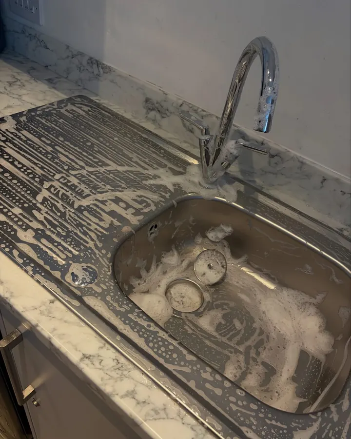 A kitchen sink full of suds part way through a clean
